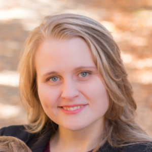 Head shot of Emily Brown with blonde hair and dark round-neck sweater.